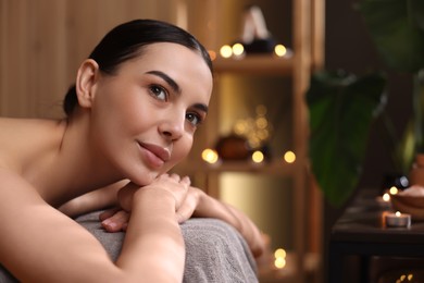 Spa therapy. Beautiful young woman lying on massage table in salon, space for text