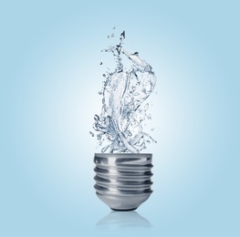 Image of Light bulb with water splashes on light blue background. Alternative energy source