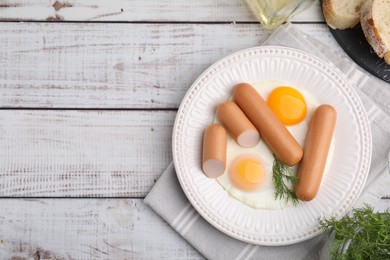 Photo of Delicious boiled sausages and fried eggs served on wooden table, flat lay. Space for text