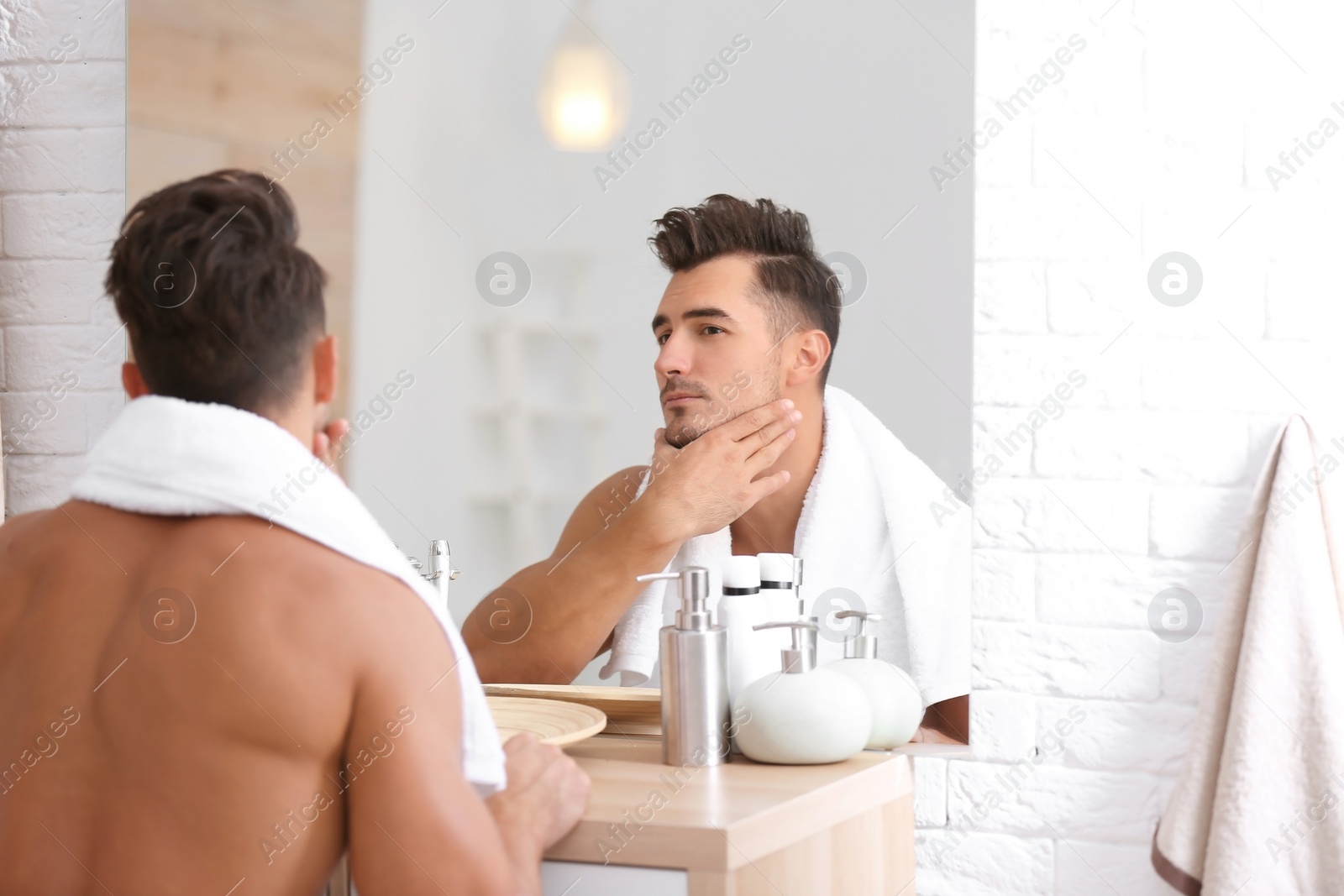 Photo of Young man with stubble ready for shaving near mirror in bathroom