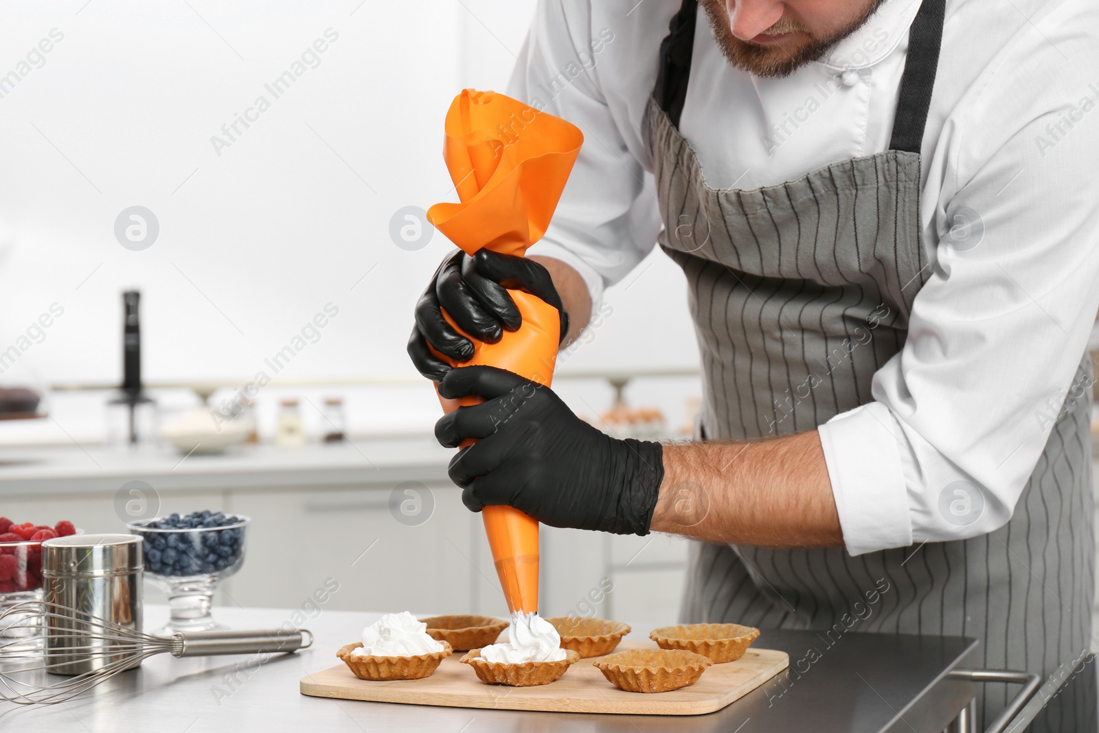 Photo of Pastry chef preparing desserts at table in kitchen, closeup