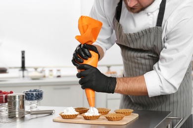 Photo of Pastry chef preparing desserts at table in kitchen, closeup