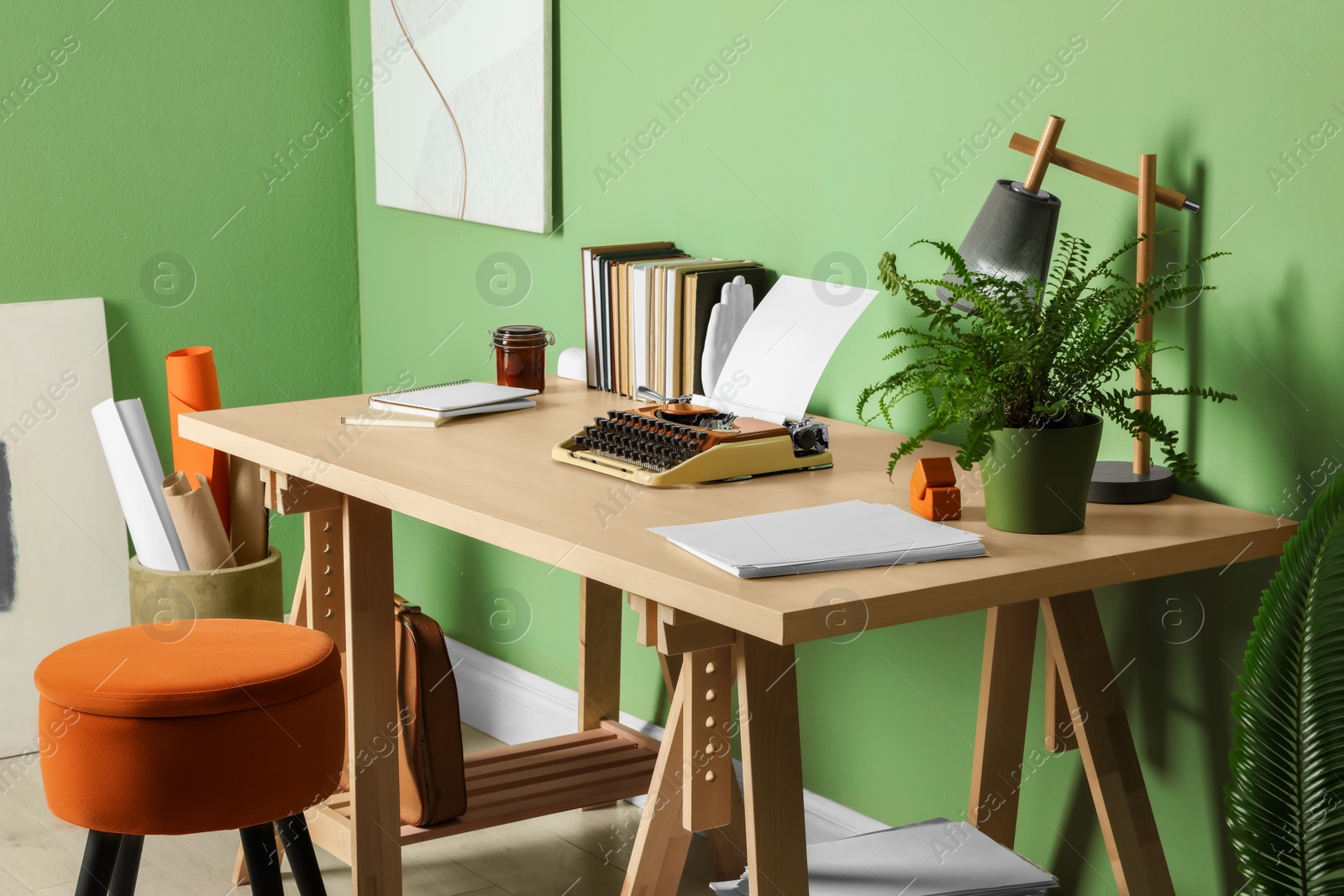 Photo of Writer's workplace with typewriter on wooden desk near pale green wall in room