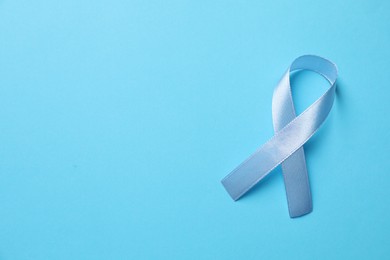 International Psoriasis Day. Ribbon as symbol of support on light blue background, top view. Space for text