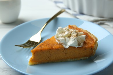 Photo of Piece of delicious pumpkin pie with whipped cream and fork on white table, closeup