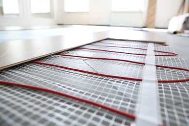 Photo of Installation of modern underfloor trace heating system indoors, closeup