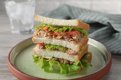 Photo of Delicious sandwich with tuna, tomatoes and lettuce on white wooden table, closeup