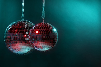 Shiny disco balls under bright cyan light, space for text