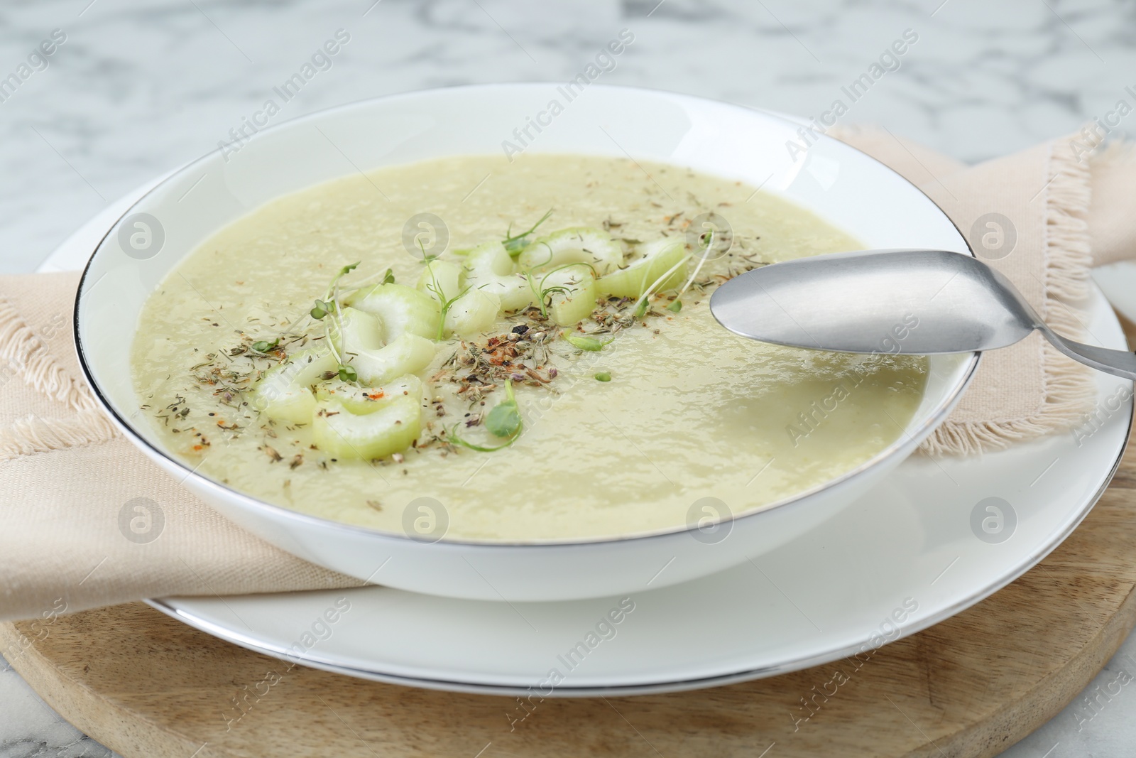 Photo of Bowl of delicious celery soup and spoon on table, closeup