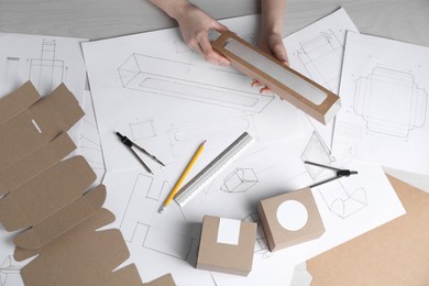 Photo of Woman creating packaging design at light wooden table, top view