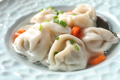 Photo of Broth with tasty dumplings in plate, closeup