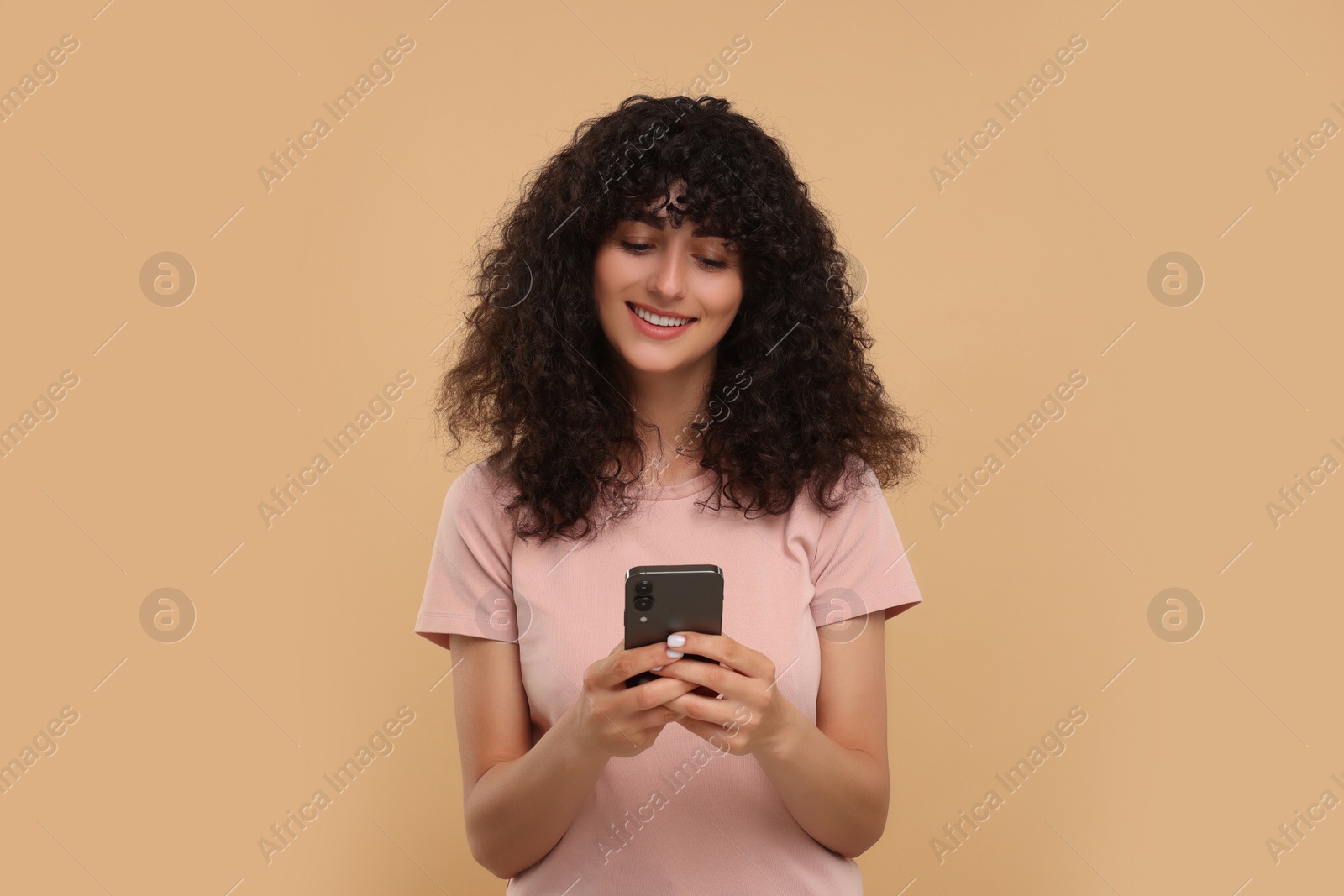 Photo of Happy young woman using smartphone on beige background