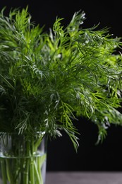 Photo of Fresh dill in glass on black background, closeup