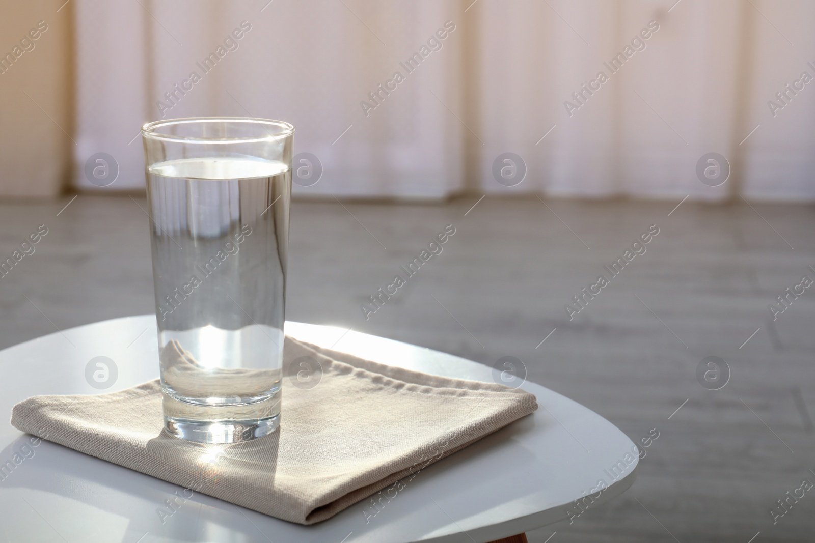 Photo of Glass of water on table against blurred background. Space for text