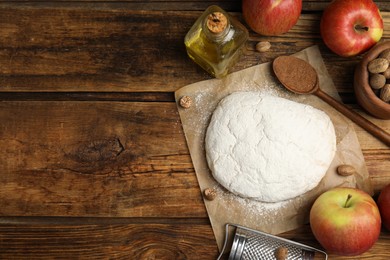 Photo of Raw dough, nutmeg seeds and other ingredients on wooden table, flat lay. Space for text