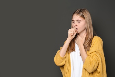 Photo of Teenage girl suffering from cough on dark background. Space for text