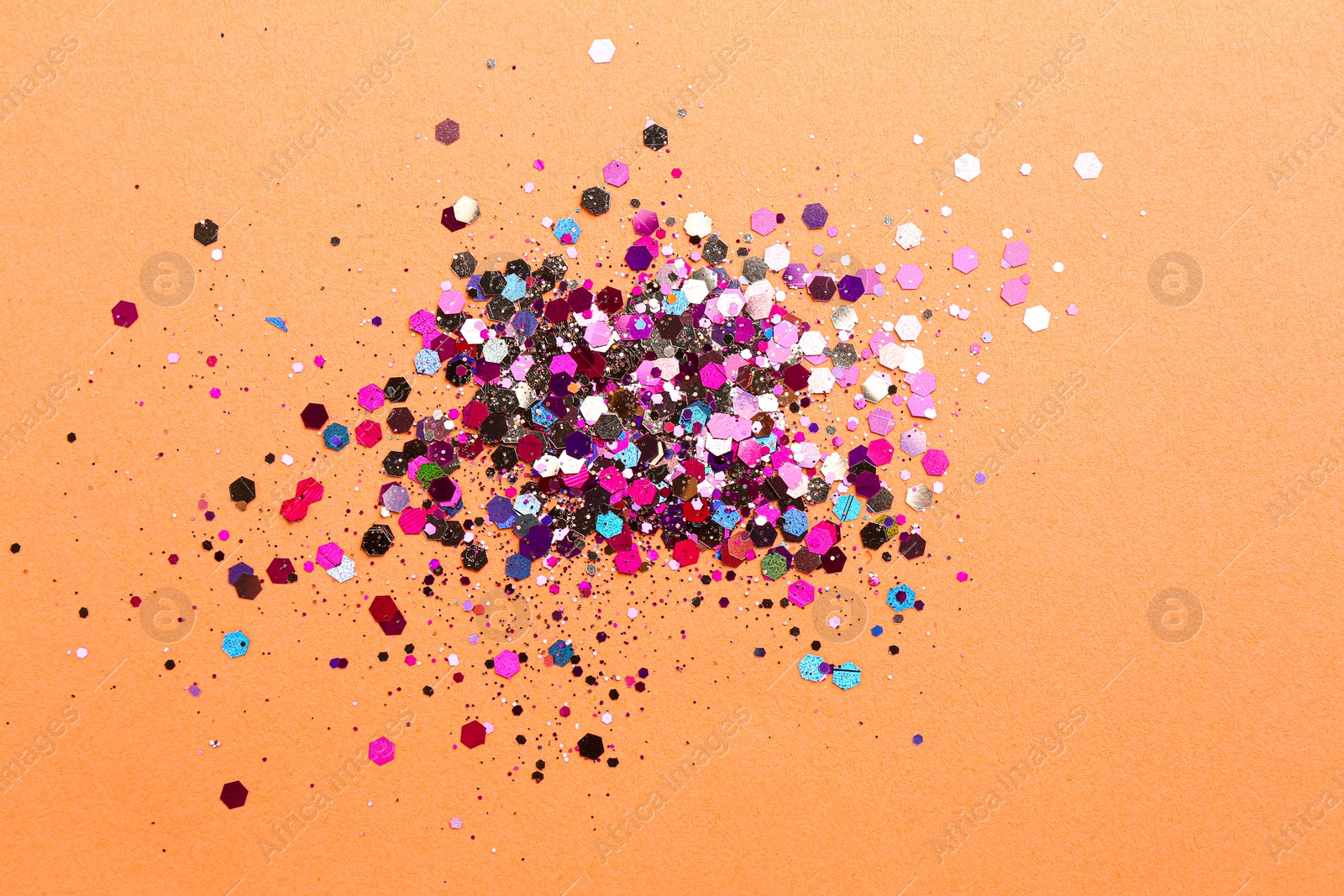 Photo of Shiny bright glitter on coral background, flat lay