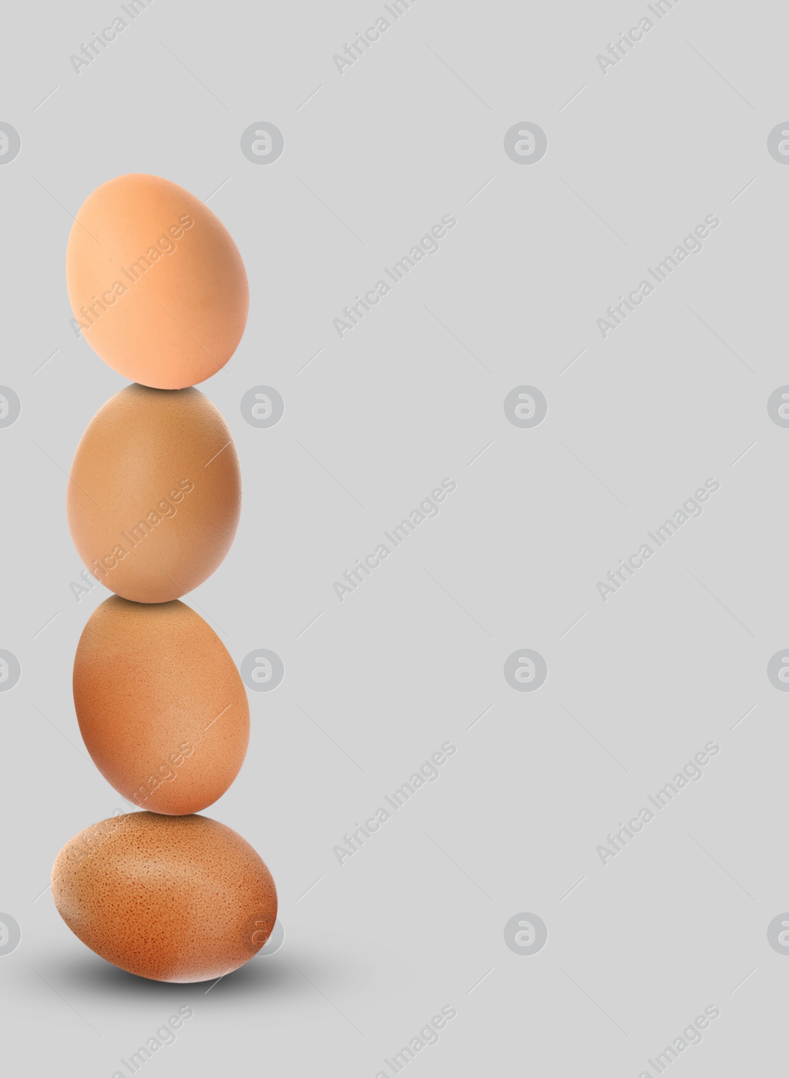 Image of Stacked fresh chicken eggs against light grey background. Space for text