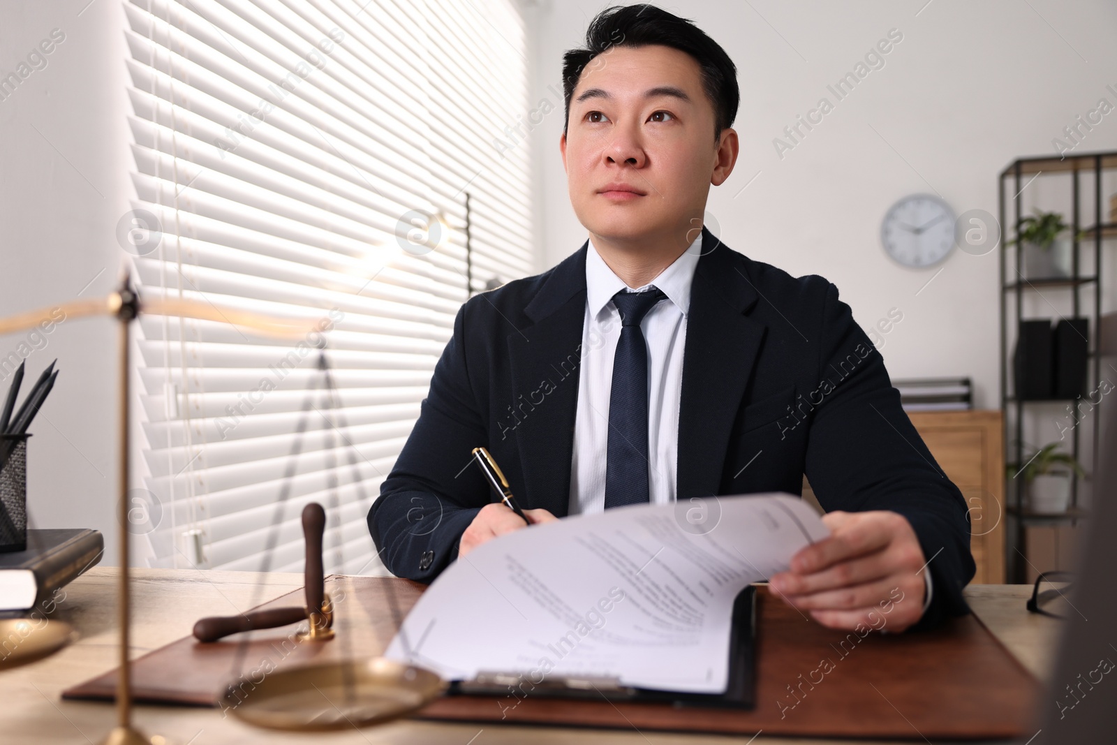 Photo of Notary writing notes at wooden table in office