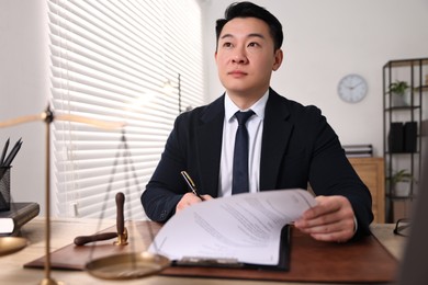 Notary writing notes at wooden table in office