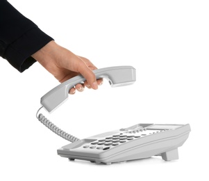 Young woman picking up telephone on white background