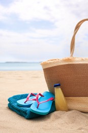 Photo of Straw bag, flip flops, towel and bottle of refreshing drink on beach