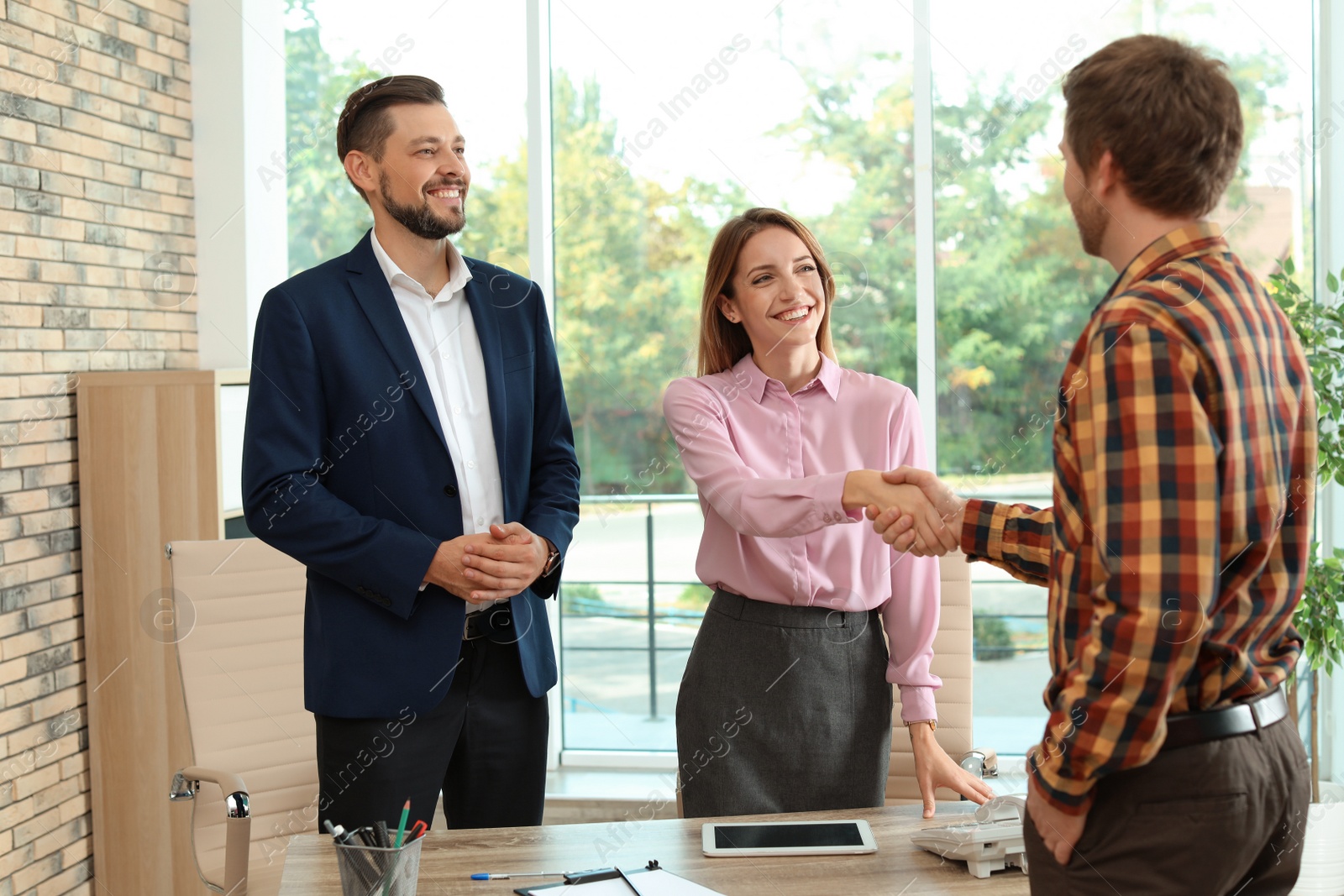 Photo of Human resources manager shaking hands with applicant during job interview in office