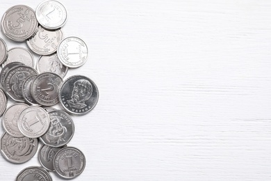 Photo of Ukrainian coins on white wooden background, flat lay. Space for text
