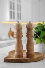 Wooden salt and pepper shakers on white table in kitchen