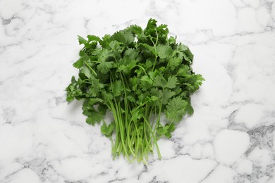 Bunch of fresh aromatic cilantro on white marble table, top view