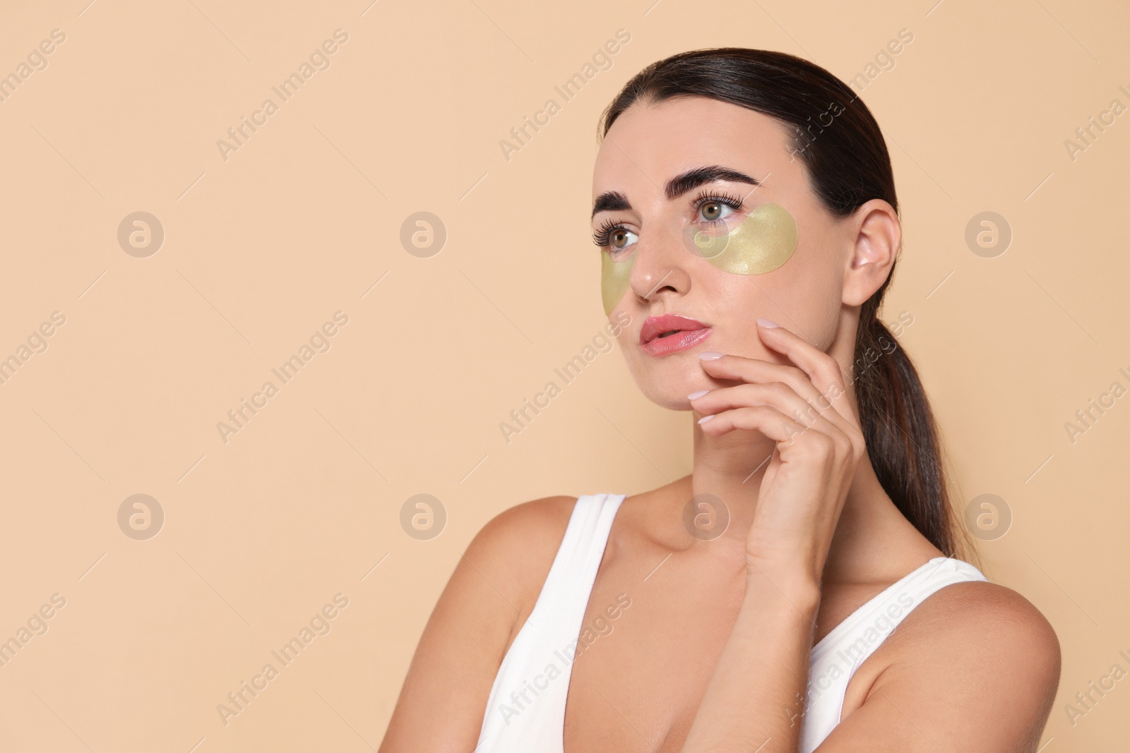 Photo of Beautiful woman with under eye patches on beige background. Space for text