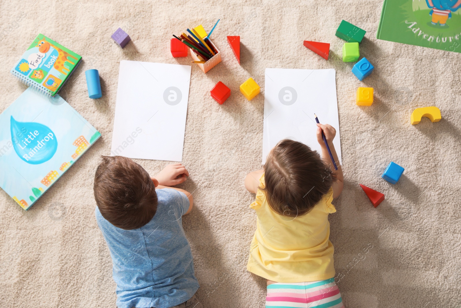 Photo of Little children drawing indoors, top view. Learning and playing