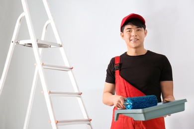 Photo of Male decorator with paint and roller indoors