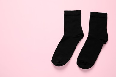 Photo of Pair of black socks on pink background, flat lay. Space for text