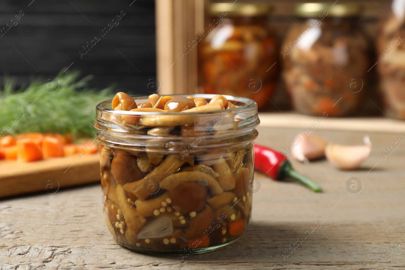 Photo of Delicious marinated mushrooms in glass jar on wooden table