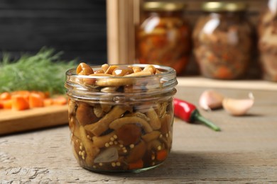 Delicious marinated mushrooms in glass jar on wooden table