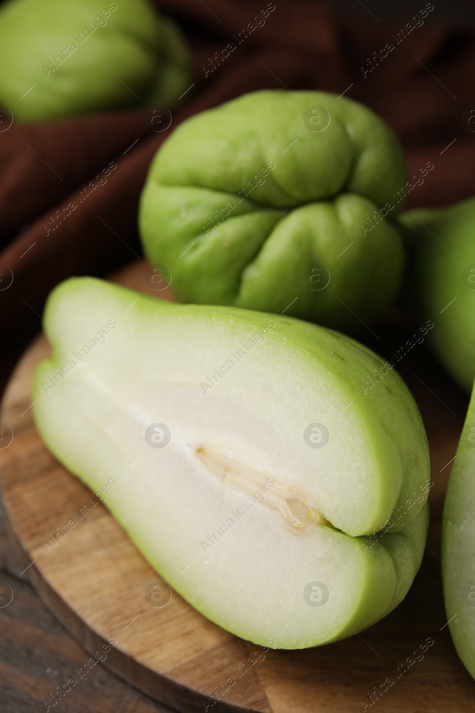 Photo of Cut and whole chayote on wooden table, closeup
