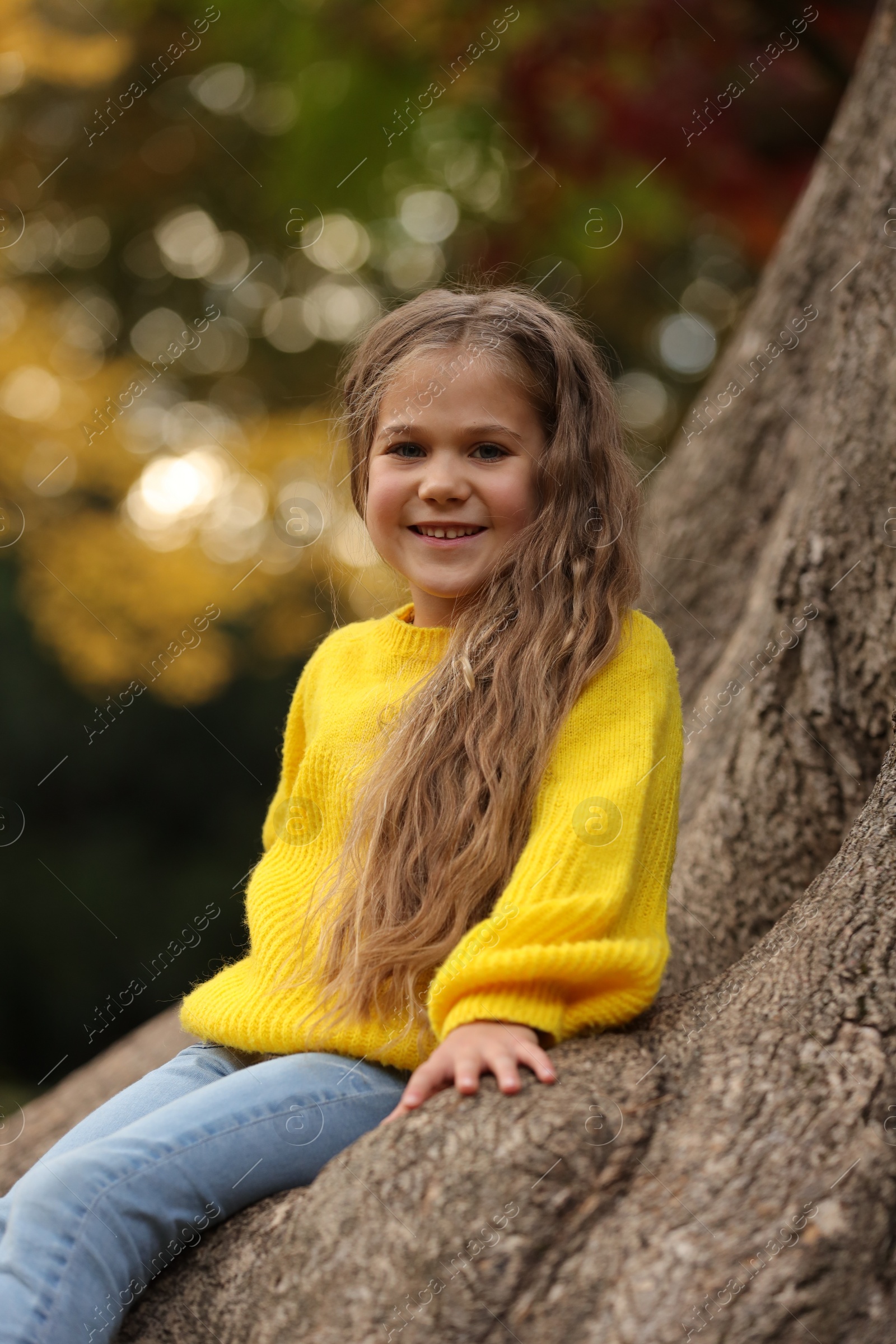 Photo of Portrait of cute girl near tree in autumn park