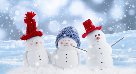 Image of Cute decorative snowmen in hats outdoors on snowy day, banner design