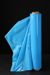 Photo of Roll of plastic stretch wrap film on table against black background