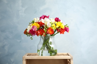 Photo of Bouquet of spring freesia flowers in vase on color background