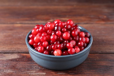 Photo of Fresh ripe cranberries in bowl on wooden table, closeup