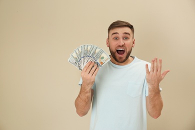 Portrait of emotional young man with money on color background. Space for text