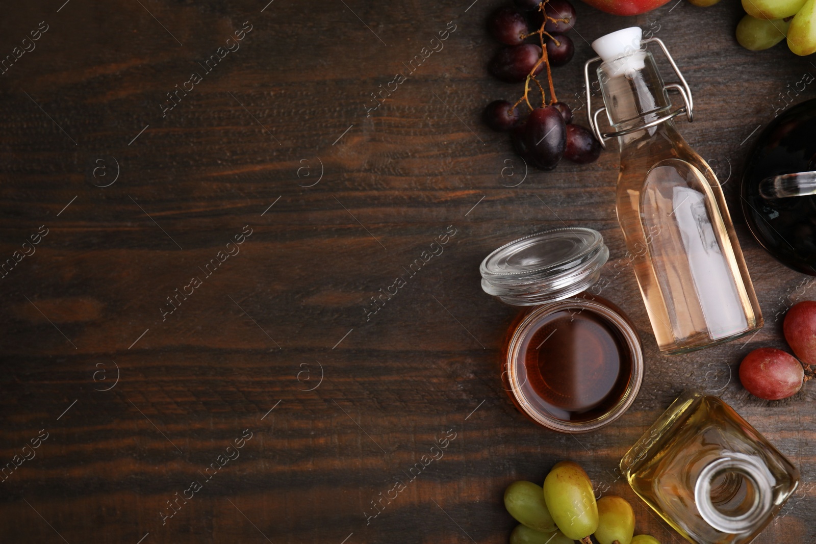 Photo of Different types of vinegar and fresh fruits on wooden table, flat lay. Space for text