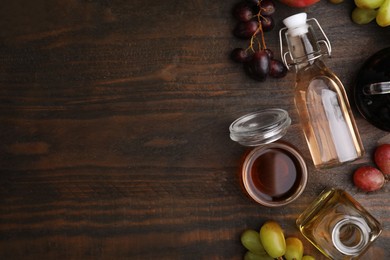 Photo of Different types of vinegar and fresh fruits on wooden table, flat lay. Space for text