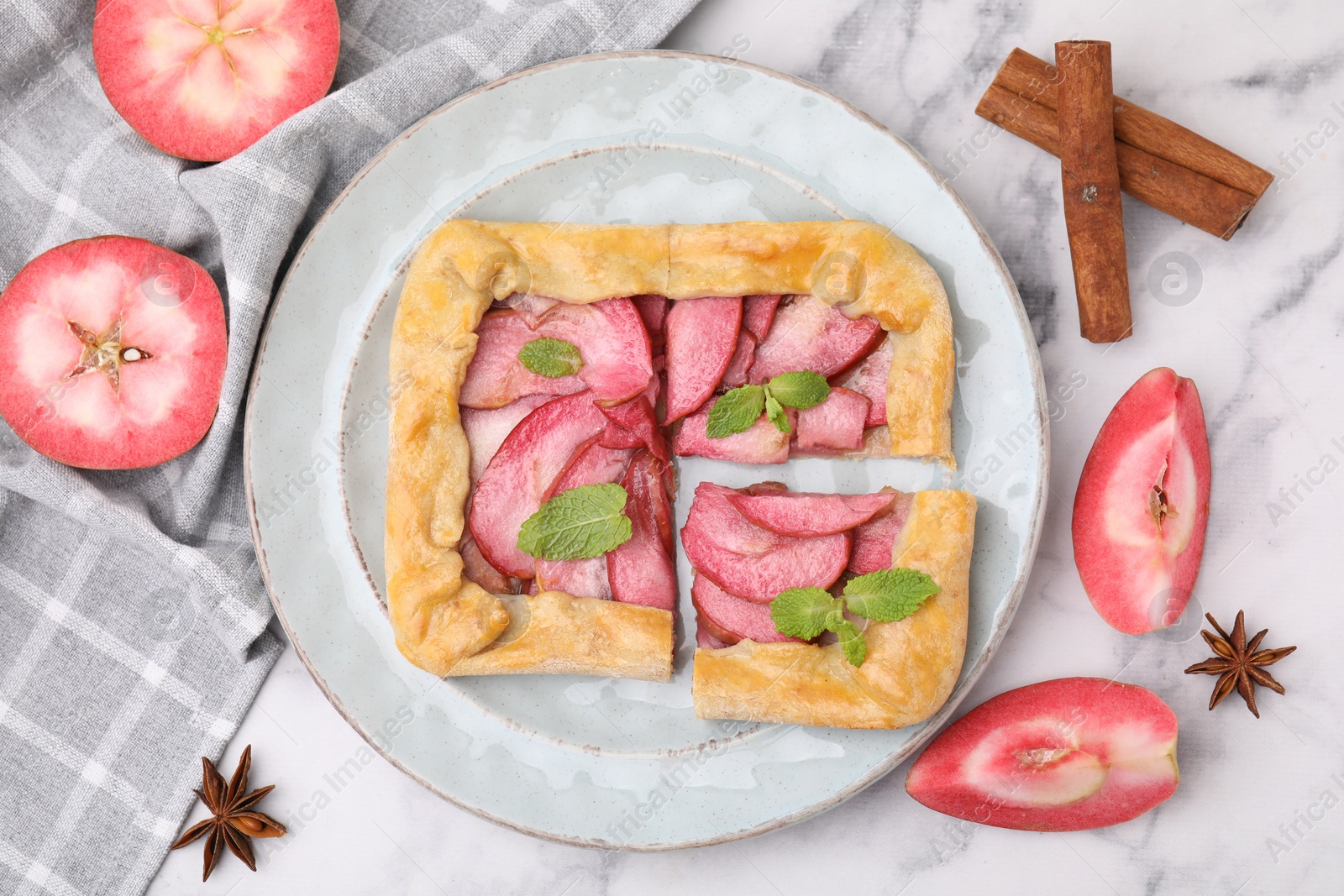 Photo of Delicious apple galette with mint and ingredients on white marble table, flat lay