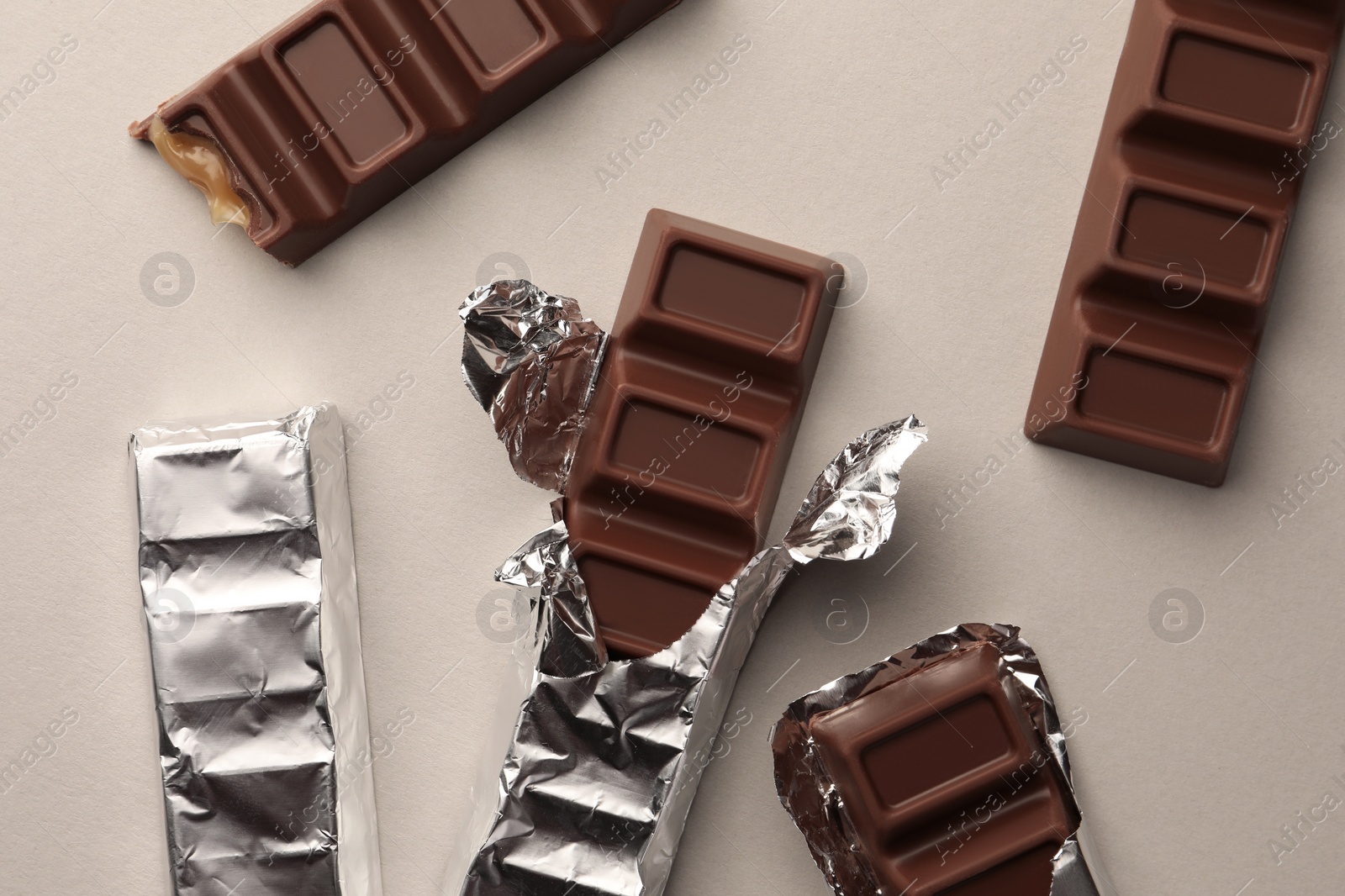 Photo of Tasty chocolate bars on light background, flat lay