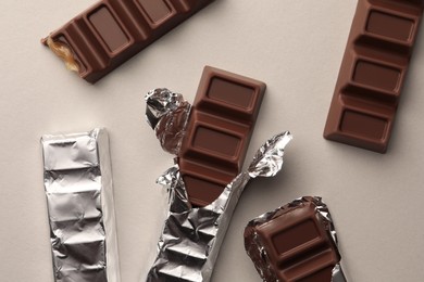 Photo of Tasty chocolate bars on light background, flat lay