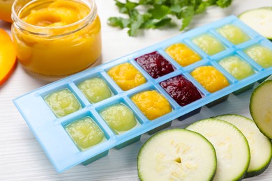 Photo of Different purees in ice cube tray and ingredients on white table. Ready for freezing
