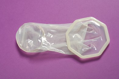 Photo of Unrolled female condom on violet background, closeup. Safe sex